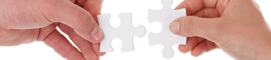 two hands each holding a white puzzle piece on white background