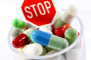 Pills in a distribution cup with a stop sign, representing dangerous drugs in civil cases.