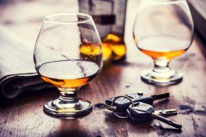 Drinks on a bar table with car keys next to them, symbolizing drunk driving