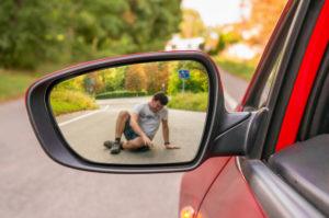 man lying in road in rearview mirror