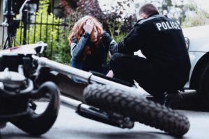 police officer checks on injured motorcyclist after traffic accident