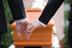 family members holding hands at a funeral