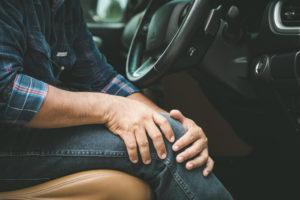 man gripping his knee after a car accident