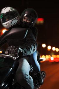 couple rides motorcycle through city at night