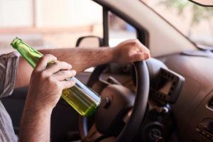 man drinks beer while driving