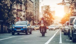 motorcycle rides along city street in traffic