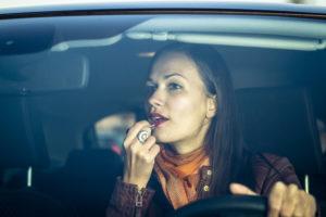 woman applies makeup while driving