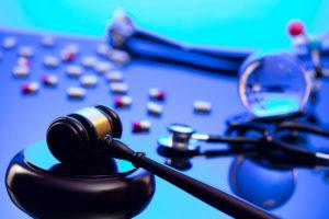 gavel and stethoscope with pills strewn about table