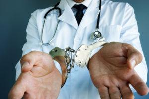 physician with stethoscope in handcuffs