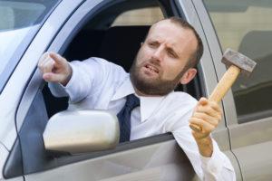 hostile motorist holding sledgehammer and pointing at another driver