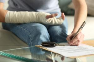 Woman with broken arm signing legal papers after a car accident