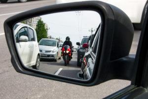 A red motorcycle driving between the lanes, dangerously close to cars.