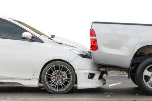 White sedan rear-ends silver pickup truck on the road