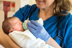 Medical worker feeding small baby