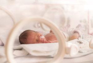 A premature infant lies in an incubator.