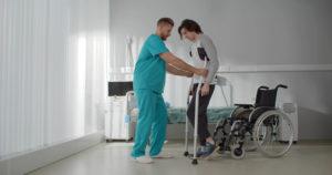 A hospital worker helps an injury victim on crutches.