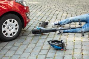 man in an accident with scooter and red car