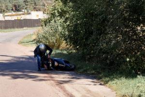 man with helmet picks his scooter up