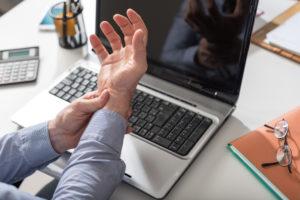 An office worker holding their wrist in pain.