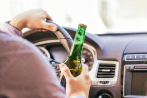 man drinking alcohol while driving a car